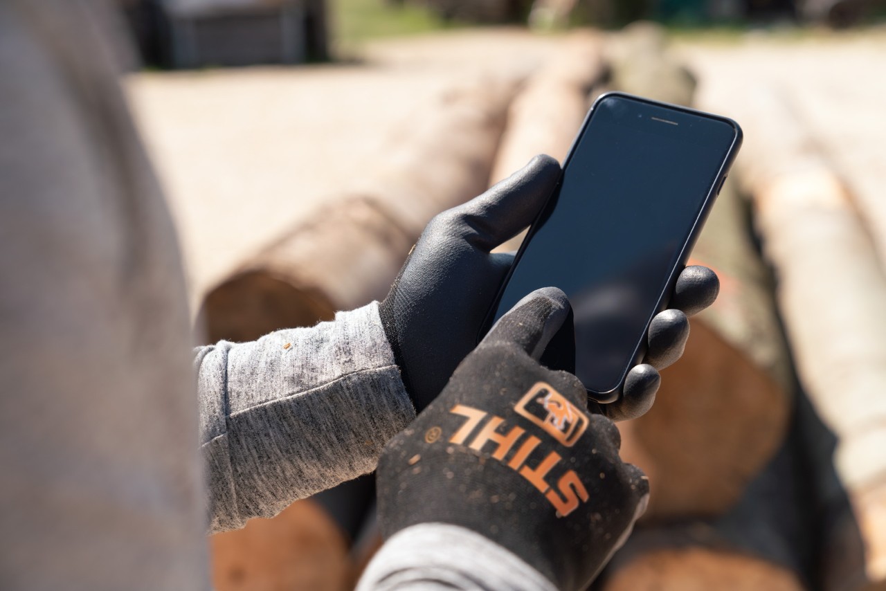Άτομο με smartphone στο χέρι και γάντια STIHL FUNCTION SENSOTOUCH